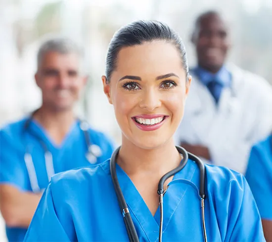 A female healthcare professional in scrubs standing with her team of doctors.