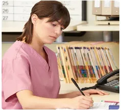 A nurse diligently writes on a piece of paper, documenting important medical information.