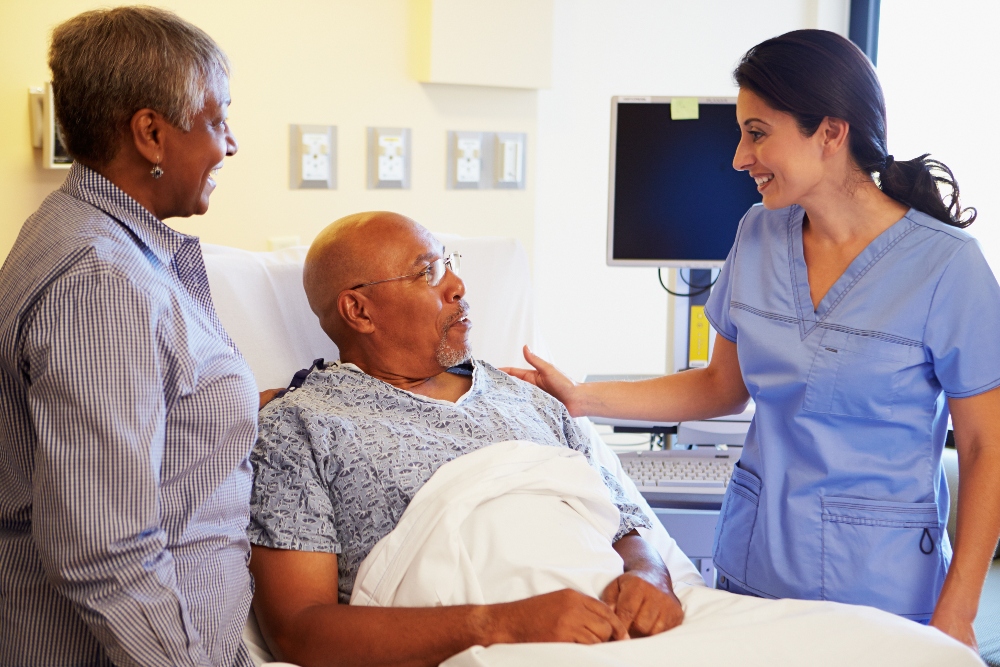 Nurse smiling at a male patient in hospital bed